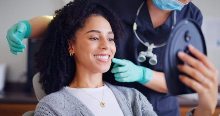 young woman smiling in a dental chair, routine exam, dentist in green gloves