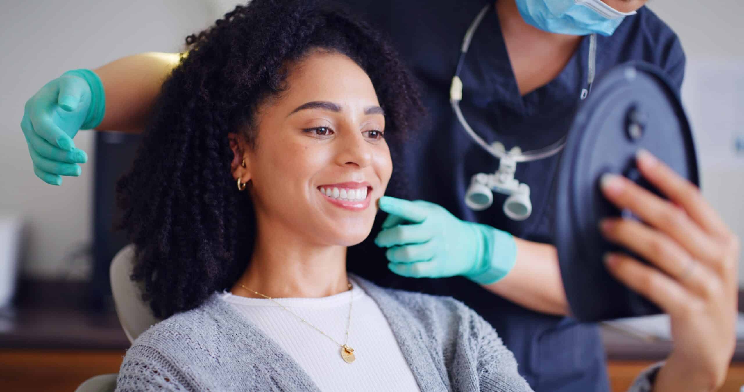young woman smiling in a dental chair, routine exam, dentist in green gloves