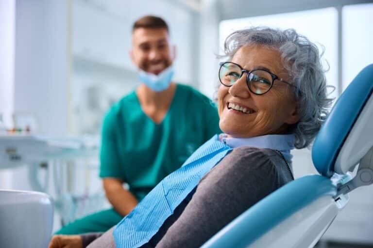 older woman smiling in a dental office, new dentures